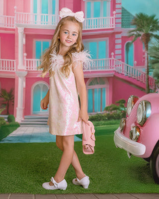 Girl in sparkly pink sequin dress holding puppy. Perfect comfortable dress for whole day event like birthday party or holiday celebration. Faeella dress with feather and sequins.