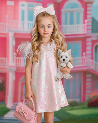 Girl in sparkly pink sequin dress holding puppy. Perfect comfortable dress for whole day event like birthday party or holiday celebration. Faeella dress with feather and sequins.