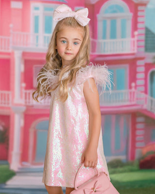 Girl in sparkly pink sequin dress holding puppy. Perfect comfortable dress for whole day event like birthday party or holiday celebration. Faeella dress with feather and sequins.
