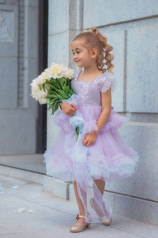 Girl wearing lavender sequin tulle dress holding white flowers. Perfect Faeella dress for itch free, comfortable flower girl moments and weddings.