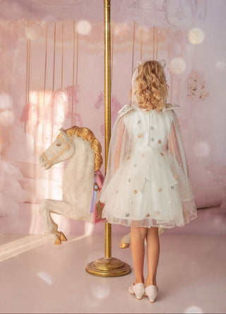 Girl in white star embroidered tulle dress with pearl details by carousel in Faeella, perfect for holiday shoot, flower girl and weddings