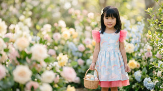 Sky-blue cloud-print Faeella Easter dress in a spring garden — small batch occasion dress for girls