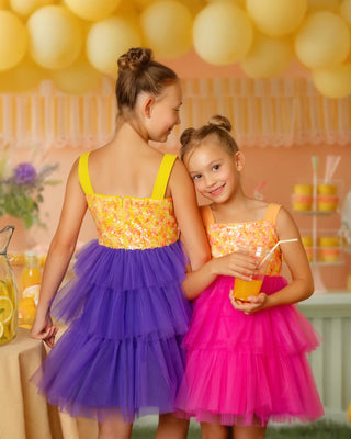 Girls in Faeella tiered tulle party dresses at a lemonade stand, hot pink Pink Lemonade birthday dress on the right